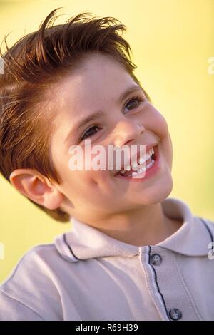 Exterior, Retrato, Nahaufnahme, 6-jaehriger Junge mit kurzen braunen Haaren, mit bekleidet beigem Polohemd, zeigt lachend sein Milchgebiss Foto de stock