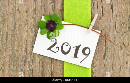 Tarjeta de Año Nuevo para el año 2019 con hojeados trébol en fondo de madera Foto de stock