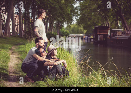 Grupo de jóvenes Hipster a orillas del río Garona, barcazas en el fondo Foto de stock