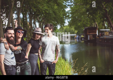 Grupo de jóvenes Hipster a orillas del río Garona, barcazas en el fondo Foto de stock