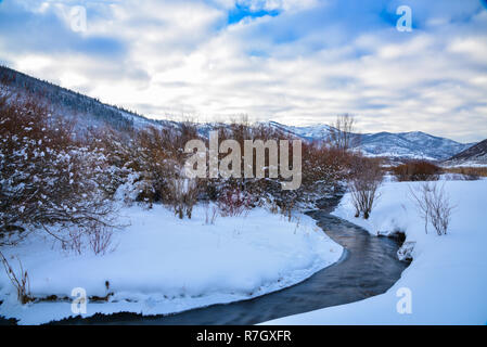 Un pequeño arroyo fluye a través de una pradera con nieve cerca de Park City, Utah.