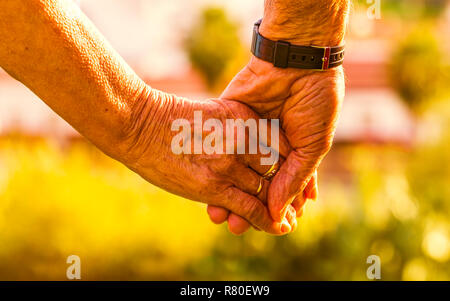 Captura recortada de la pareja de ancianos cogidos de la mano al atardecer al aire libre. Se centran en las manos