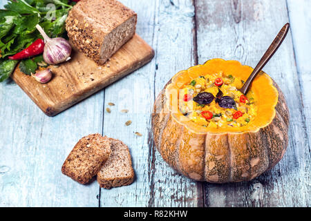 Sopa de Lentejas con decorados en la calabaza tallada con trozos de pan en el fondo de madera azul en vacaciones de otoño Foto de stock