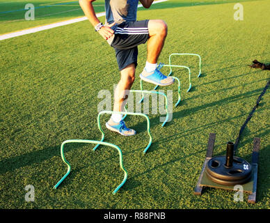 Un atleta obtiene cierta agilidad la capacitación realizada por corriendo sobre mini vallas lateralmente