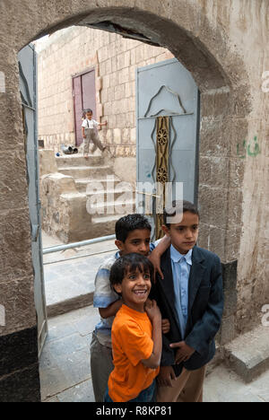 Tres niños desnudos jugando en el mar Arábigo en la playa Mahim en