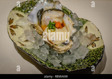 Rock, salsa ponzu ostras, huevas de salmón, cebolleta sobre un lecho de hielo Foto de stock