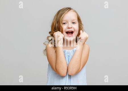 Niña niña en orejeras y ropa cálida gritando con alegría sobre fondo gris  Fotografía de stock - Alamy