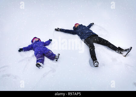 Madre e hijo hacer ángeles en la nieve. Foto de stock