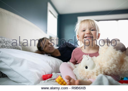 Feliz retrato Niño niña jugando con un mono de peluche en la cama