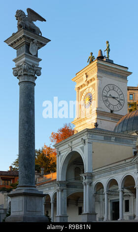 Loggia de Saint James, el león alado de San Marcos y la torre del reloj de la columna al anochecer en Libertà en Udine, Italia Foto de stock