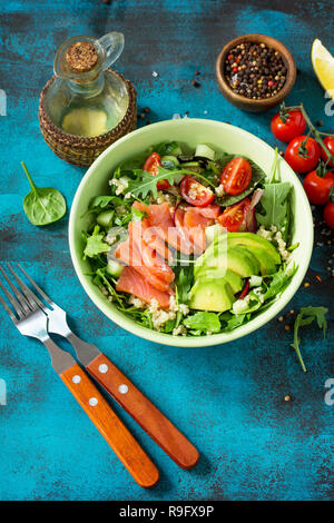 Menú de la dieta, la alimentación vegetariana. Ensalada Saludable con quinoa, rúcula, tomates, el salmón y el Aguacate en azul mesa de piedra o de hormigón. Foto de stock