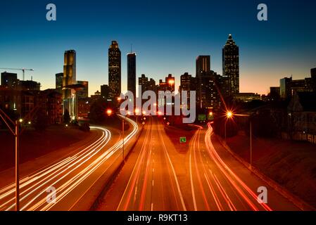 Atlanta Downtown skyline iluminado al atardecer, por autopista en hora punta, en Atlanta, Georgia, EE.UU. Foto de stock