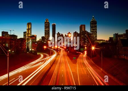 Atlanta Downtown skyline iluminado al atardecer, por autopista en hora punta, en Atlanta, Georgia, EE.UU. Foto de stock