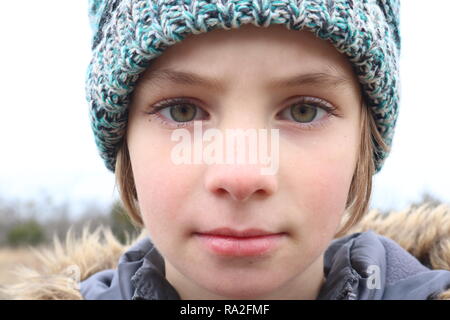 Retrato de una niña con ojos verde intenso con un gorro en el frío invierno