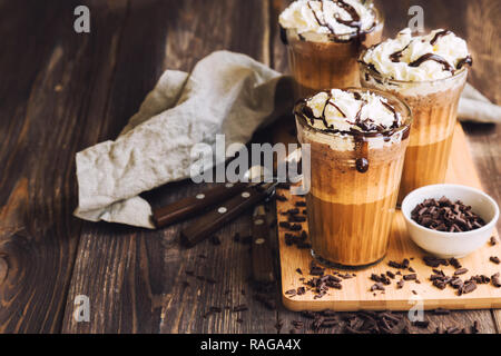 Cóctel de café casero con crema batida y chocolate líquido sobre fondo de madera rústica