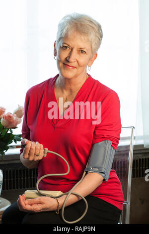 Senior Citizen monitorea la presión sanguínea en la casa, EE.UU. Foto de stock