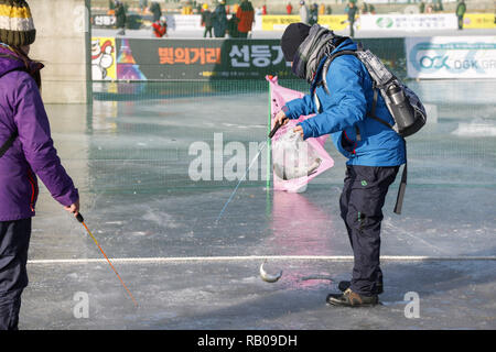 Hwacheon, Corea del Sur. 5 de enero, 2019. Enero 5, 2019-Hwacheon, Sur Korea-Visitors líneas fundido a través de orificios perforados en la superficie de un río congelado durante un concurso de captura de trucha en Hwacheon, Corea del Sur. El concurso es parte de un festival anual de hielo que atrae a más de un millón de visitantes cada año. Crédito: Ryu Seung-Il/Zuma alambre/Alamy Live News Foto de stock