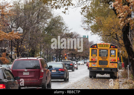 MONTREAL, Canadá - 6 de noviembre de 2018: North American Bus Escolar amarillo aparcado en la calle, a la espera de estudiantes con autos pasando por con información i