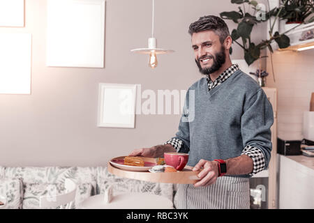 Feliz alegre hombre llevar comida a la mesa