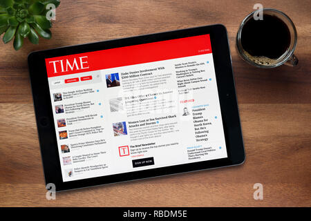 El sitio web de la revista Time es visto en un iPad, en una mesa de madera junto con un café espresso y una planta de casa (Editorial). Foto de stock