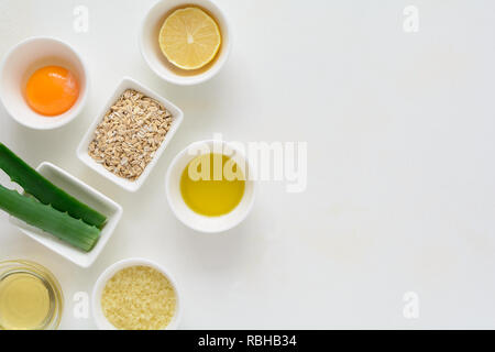 Los ingredientes frescos para el acné remedios caseros eficaces sobre fondo  blanco. Miel, sal marina, yema de huevo, aceite de oliva, avena, limón y  aloe. Sentar planas. Copiar Fotografía de stock -