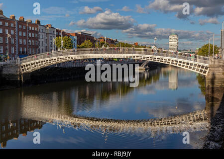 La gente camina sobre el Ha'Penny Bridge sobre el río Liffey en Dublín, Irlanda. Foto de stock