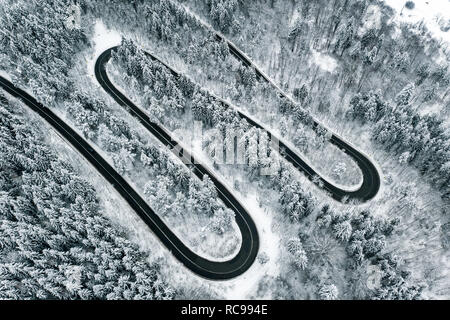 A través de un sinuoso camino de montaña en la temporada de invierno de carretera nevada Foto de stock