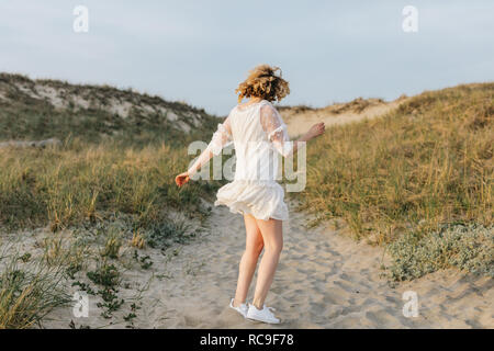 Mujer joven en vestido blanco bailando en dunas costeras, Menemsha, Martha's Vineyard, Massachusetts, EE.UU. Foto de stock