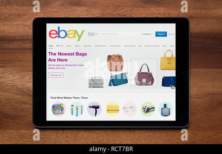 El sitio web de Ebay es visto en un iPad, que descansa sobre una mesa de madera (uso Editorial solamente). Foto de stock