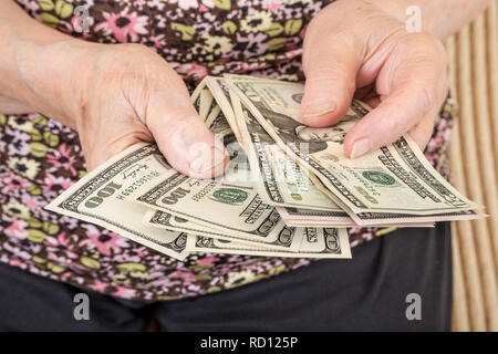 Primer plano de manos de una mujer mayor contando Dólares americanos Foto de stock