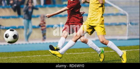 Dos jóvenes futbolistas chutar un balón de fútbol. Fútbol Fondo Horizontal. Los jóvenes atletas Junior en rojo y amarillo Camisetas de fútbol