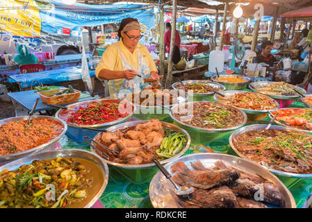 Ao Nang / en Krabi, Tailandia - Julio 5, 2018: Una mujer vende diversos platos tailandeses en un mercado. Foto de stock