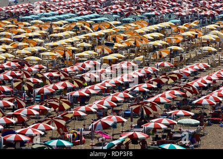 Sombrillas y reposeras para tomar sol, el turismo de masas en la playa de Caorle, Mar Adriático, Italia, Europa Foto de stock