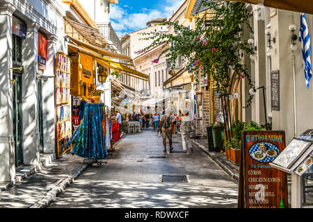Atenas, Grecia - 22 de septiembre de 2018: los turistas recorren las calles alineadas con tiendas de souvenirs y cafés al aire libre en la turística Plaka sección