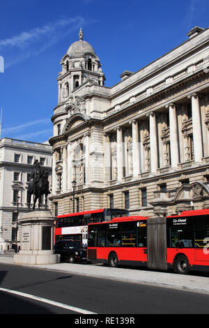 Estatua ecuestre de Prince George, el Duque de Cambridge, un taxi negro de Londres y un autobús de dos pisos de color rojo delante del antiguo edificio de la Oficina de guerra Foto de stock