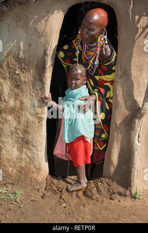 Masai madre y su hijo en la entrada de una choza, Masai Mara, Kenia, África Oriental Foto de stock