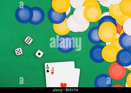 Vista superior de la mesa de póquer verde con chips multicolores, cubos y dos ases desplegada Foto de stock
