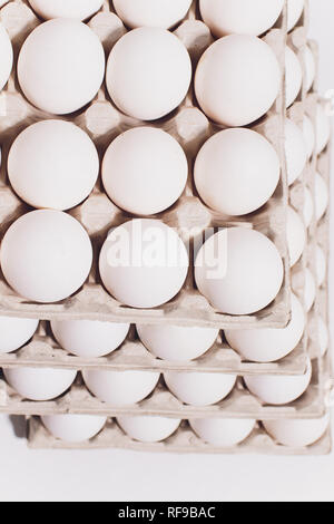 Huevos blancos de una gallina en inofensivos, embalaje de cartón sobre un fondo blanco. 5 paquetes Foto de stock