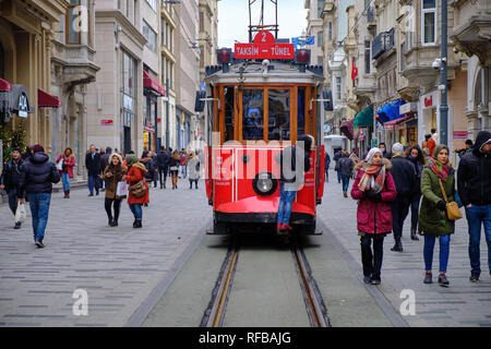 Estambul, Turquía - El Tranvía rojo haciendo su camino a través de la multitud de compradores en la avenida Independencia. Kid cabalgando sobre el exterior del tranvía Foto de stock