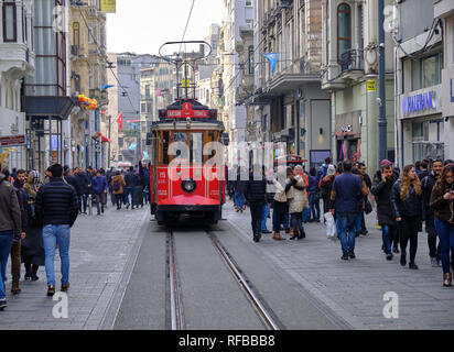 Estambul, Turquía - Diciembre 2018 - Tranvía rojo haciendo su camino a través de la multitud de compradores en la avenida Independencia. Foto de stock