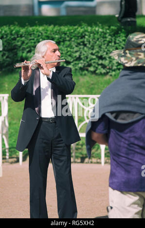 Tsarskoye Selo, San Petersburgo, Rusia - May 20, 2016: Calle músico altos hombre toca la flauta delante de los turistas en el muelle Foto de stock