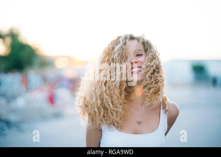 Retrato de mujer joven feliz con tirabuzones rubios