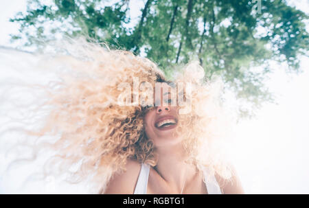 Retrato de mujer joven feliz con tirabuzones rubia a contraluz
