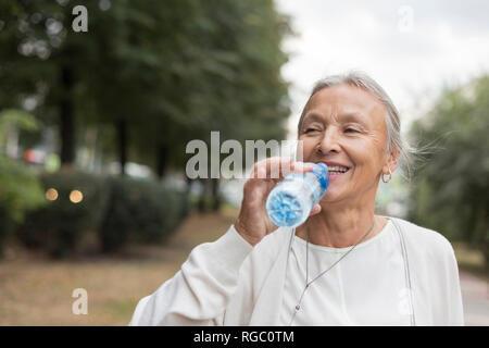 Feliz mujer senior en el exterior de la botella de agua potable