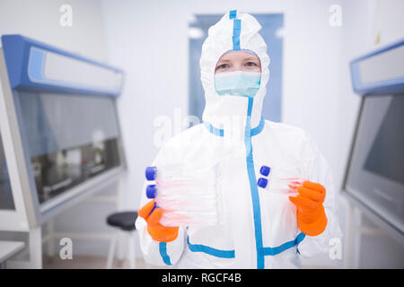 Técnico de laboratorio usando recipientes de cultivo celebración global para salas limpias