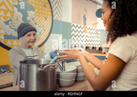 Senior positiva mujer toma su sopa caliente