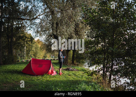 Hombre de camping en Estonia, beber café, viendo el amanecer Foto de stock