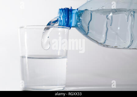 Llenar un vaso de agua con una botella de plástico. Foto de stock