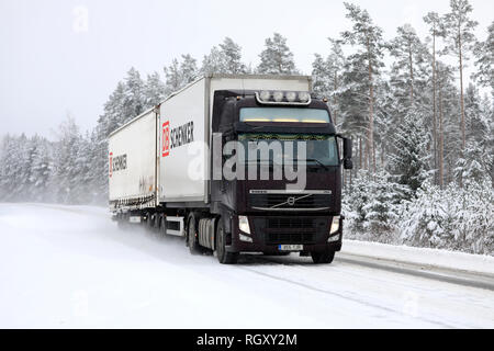 Salo, Finlandia - 25 de enero de 2019: Castaño oscuro FH Volvo Truck pulls DB Schenker doble remolque en carretera con nieve en el sur de Finlandia en la nieve invernal. Foto de stock
