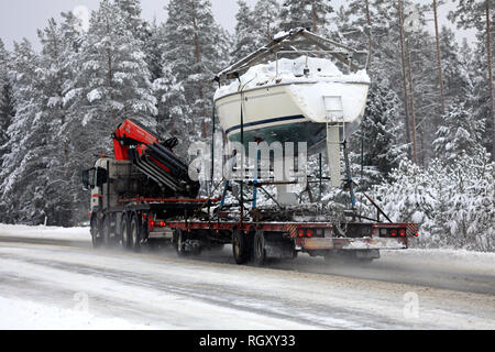 Salo, Finlandia - 25 de enero de 2019: Volvo Truck lances un bote de vela en el remolque por carretera rural en el sur de Finlandia en la nieve invernal, vista trasera. Foto de stock